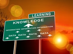 Large signpost with text (Data, Information, Knowledge), connected by arrows. Additional sign above, Text: Learning, in front of sunset